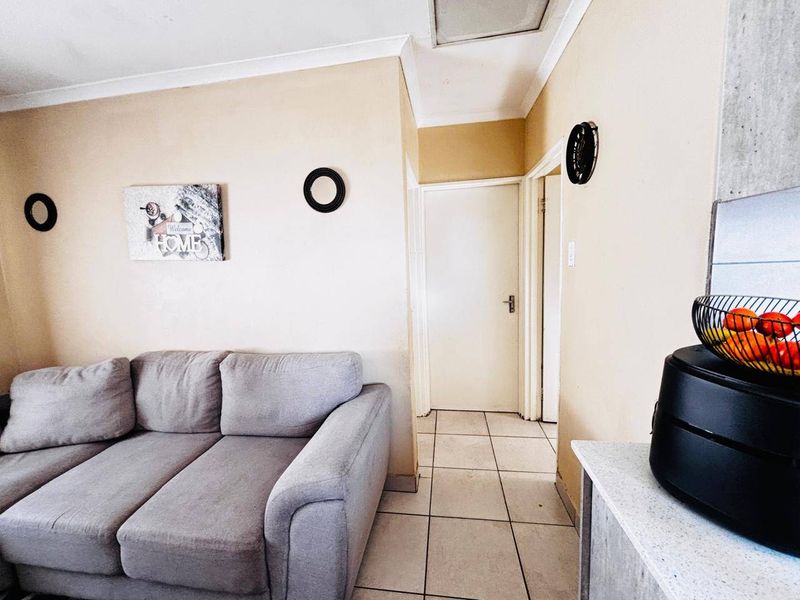 A living area featuring neutral wall tones, tiled flooring, and coved ceiling details, providing a functional and accessible space.
