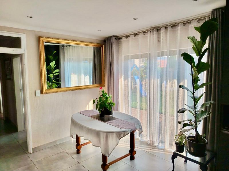 A bright living area featuring neutral tiled flooring, recessed downlighting, and large sliding glass doors providing natural light and access to the garden.