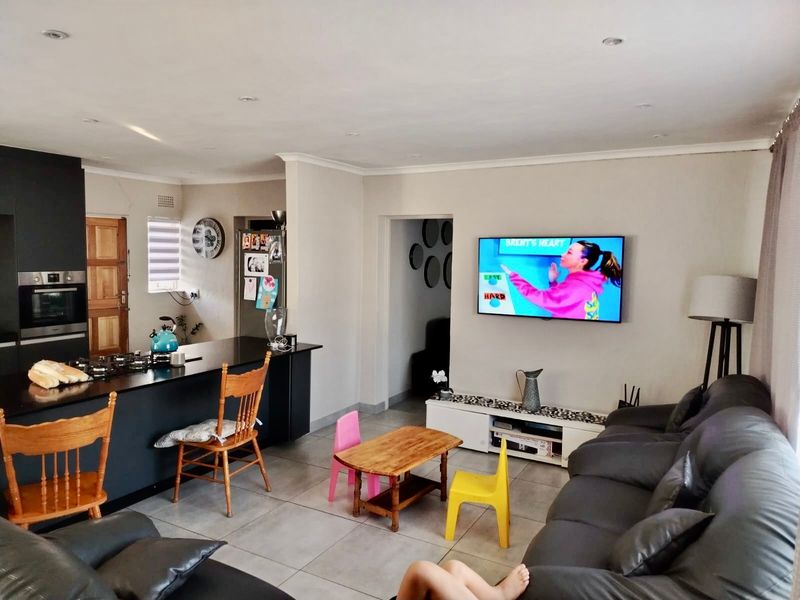 Open-plan living area featuring a modern kitchen island with a gas hob, built-in oven, and tiled flooring throughout the combined kitchen and lounge space.