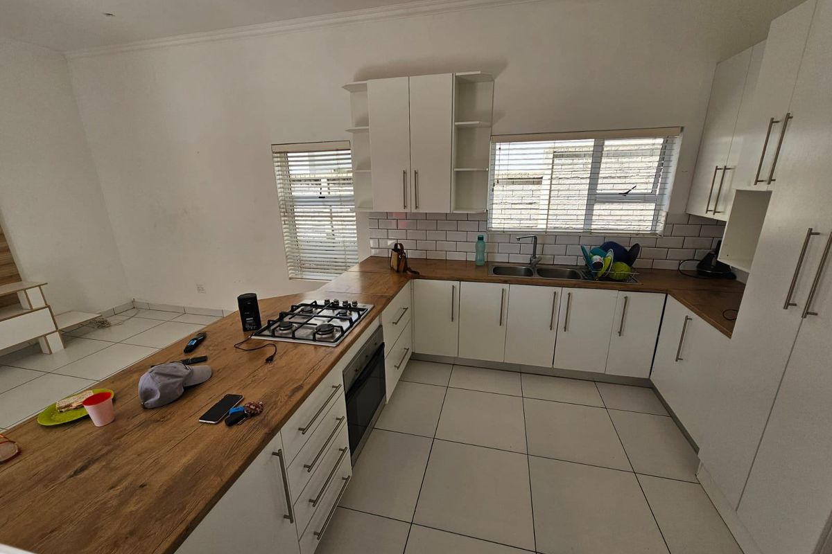 Modern kitchen featuring white cabinetry, wooden countertops, a gas hob, built-in oven, and a subway tile backsplash with tiled flooring.