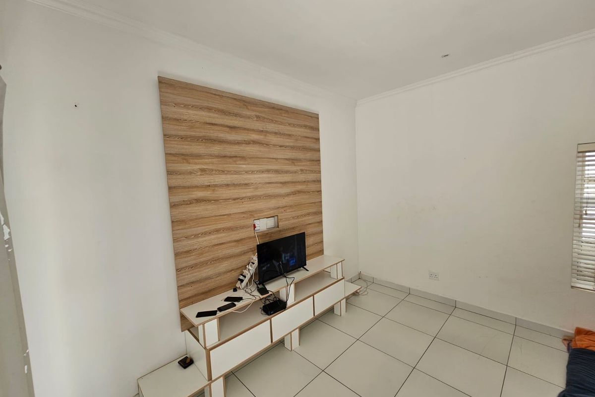 Living room featuring tiled flooring and a built-in wood-look media wall panel with integrated shelving.