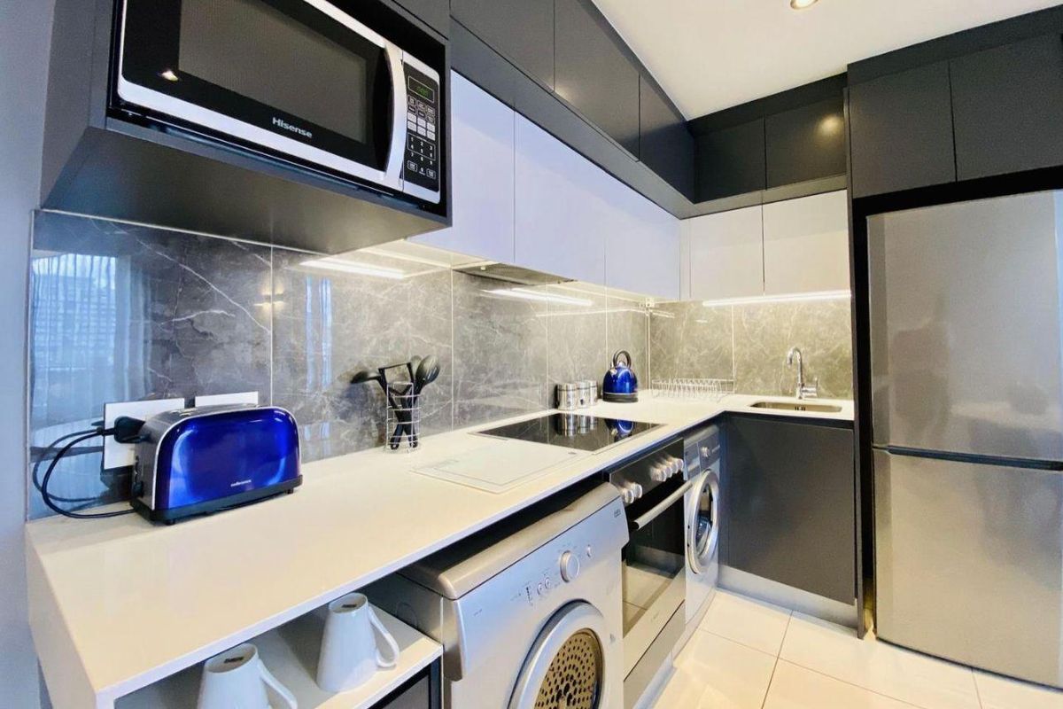 Modern kitchen featuring sleek two-tone cabinetry, stone countertops, marble-look splashback, integrated appliances, and high-quality finishes throughout.