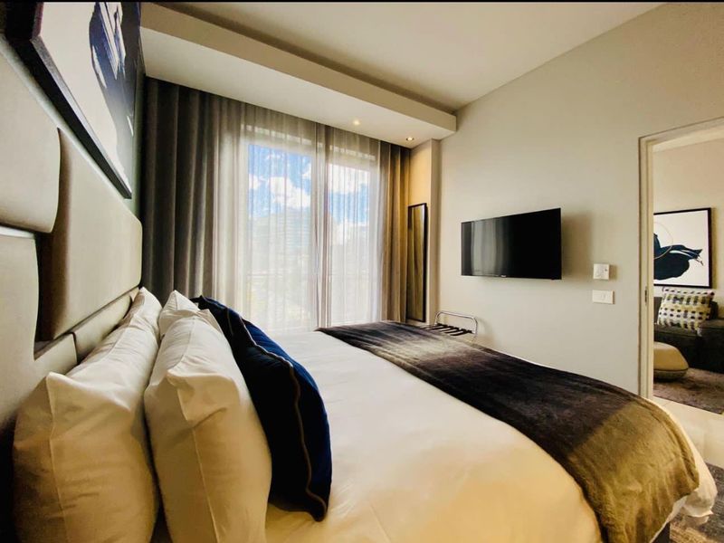 A well-maintained bedroom featuring recessed ceiling lighting, a wall-mounted television, and a sliding glass door leading to an outdoor area.