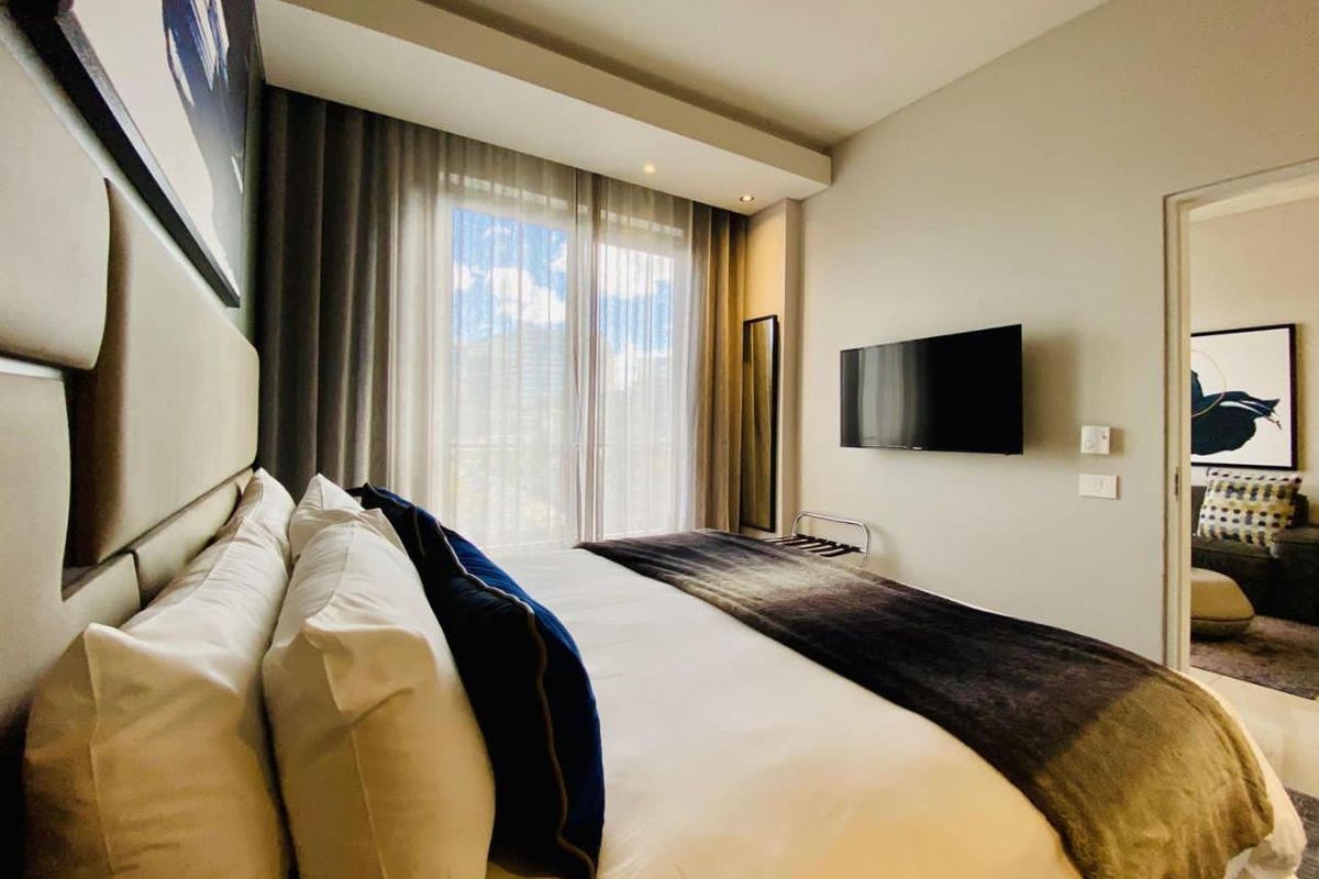 A well-maintained bedroom featuring recessed ceiling lighting, a wall-mounted television, and a sliding glass door leading to an outdoor area.