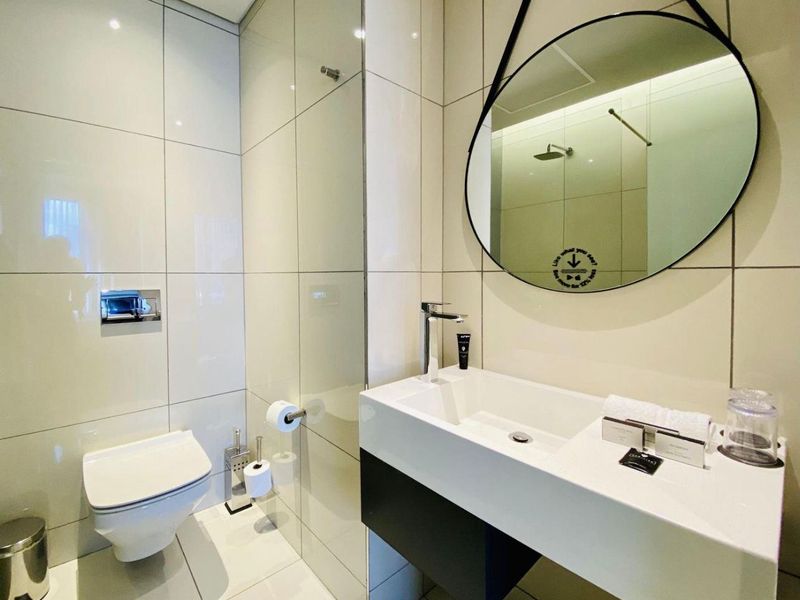 Modern bathroom featuring a wall-mounted toilet with concealed cistern, glass shower enclosure, and a sleek vanity basin with contemporary fixtures.