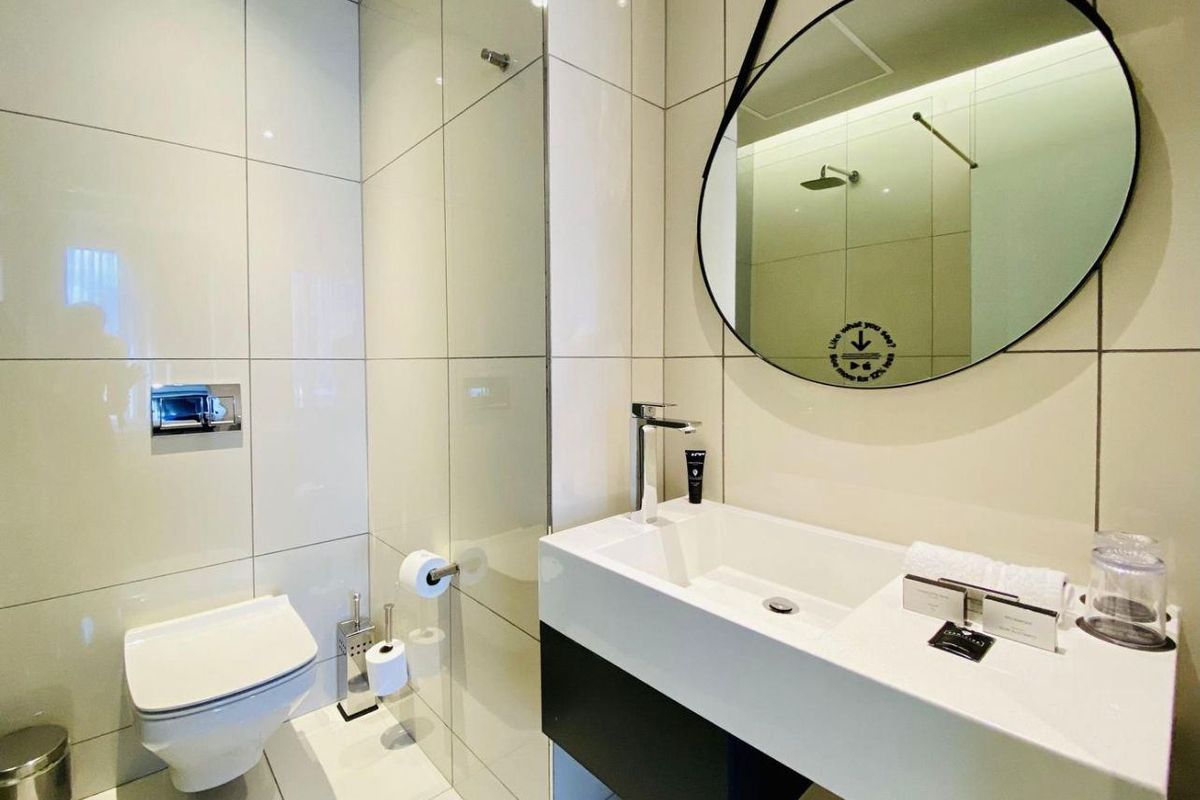 Modern bathroom featuring a wall-mounted toilet with concealed cistern, glass shower enclosure, and a sleek vanity basin with contemporary fixtures.