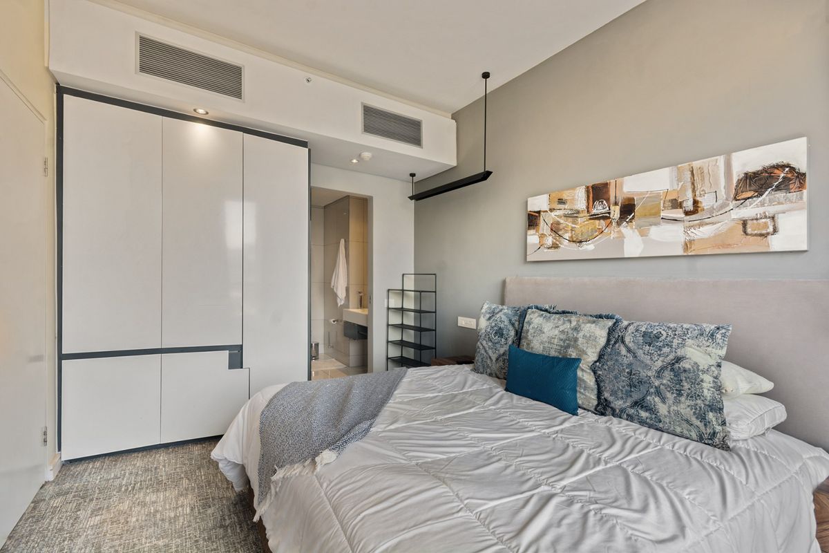 A well-maintained bedroom featuring built-in wardrobes, ducted air conditioning, and direct access to an en-suite bathroom.