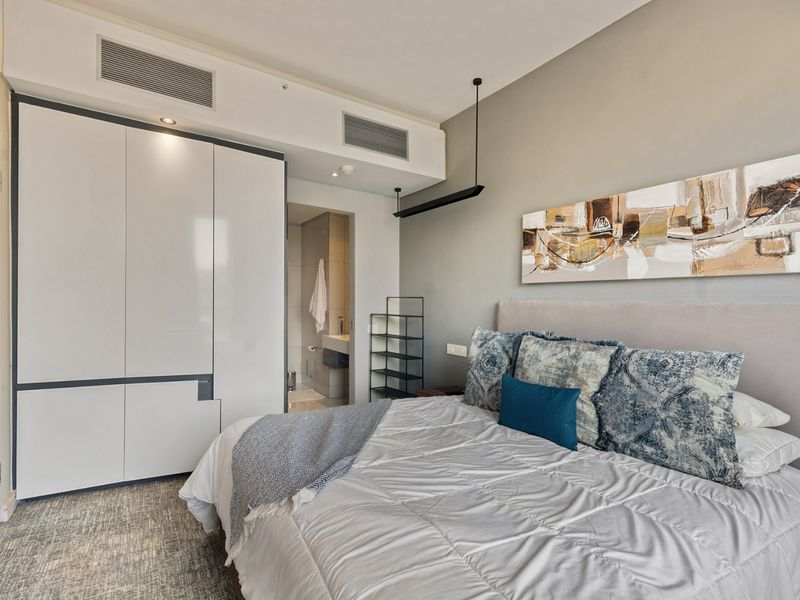A well-maintained bedroom featuring built-in wardrobes, ducted air conditioning, and direct access to an en-suite bathroom.