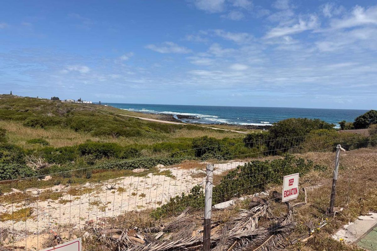 A scenic coastal view overlooking the ocean and natural landscape, featuring wire fencing and a marked deep excavation area on the property.