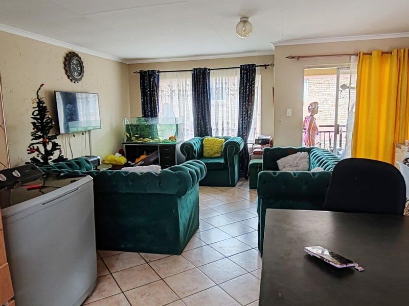 Open-plan living area featuring tiled flooring and a sliding glass door leading to an outdoor space, offering a versatile layout for dining and relaxation.