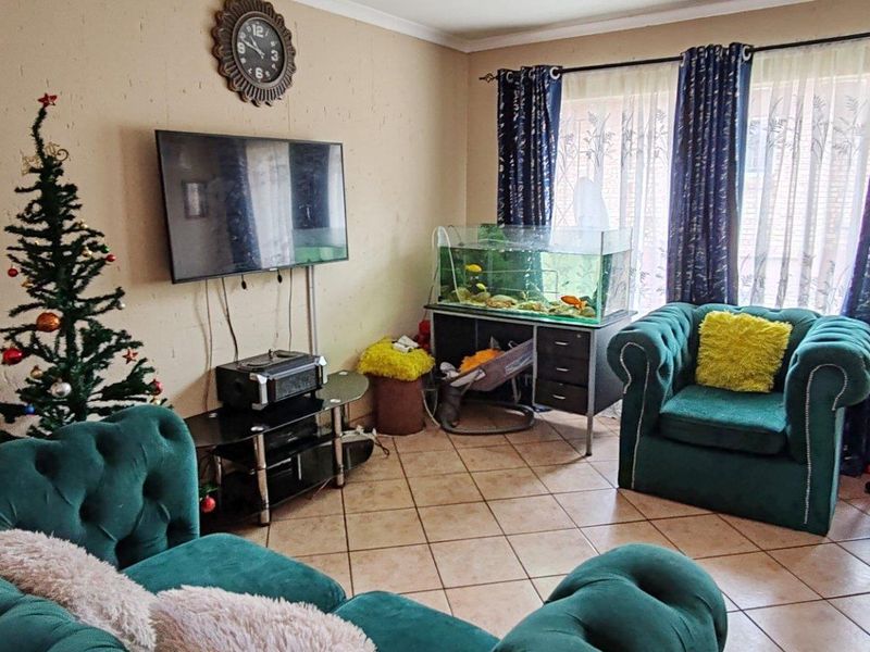 A living room featuring tiled flooring and large windows with curtain rails, offering a functional space for relaxation.