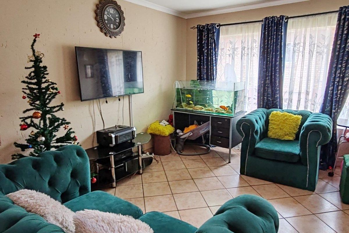 A living room featuring tiled flooring and large windows with curtain rails, offering a functional space for relaxation.