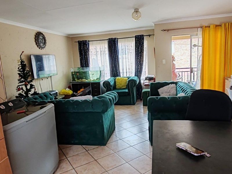 Open-plan living area featuring tiled flooring and a sliding door leading to a balcony, providing a functional layout for daily living.