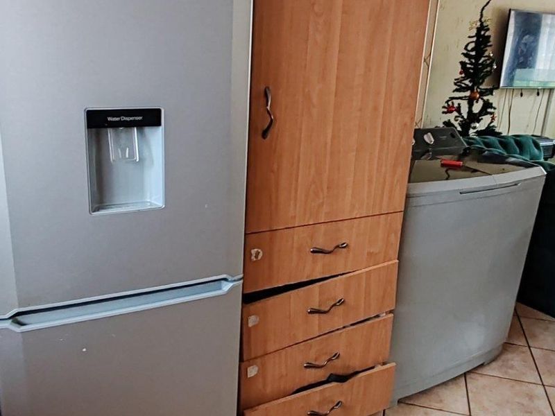 Kitchen area featuring tiled flooring and built-in cabinetry with visible wear and damage to the drawer units.