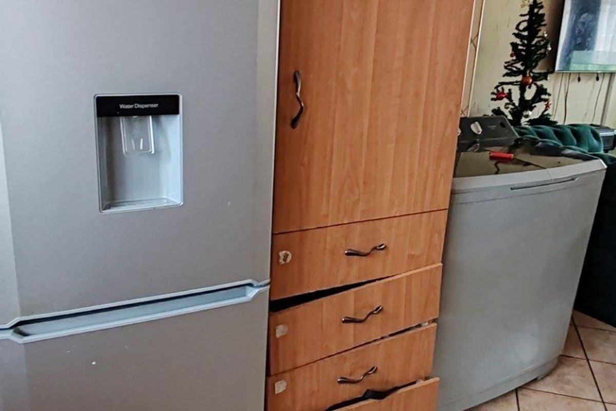 Kitchen area featuring tiled flooring and built-in cabinetry with visible wear and damage to the drawer units.