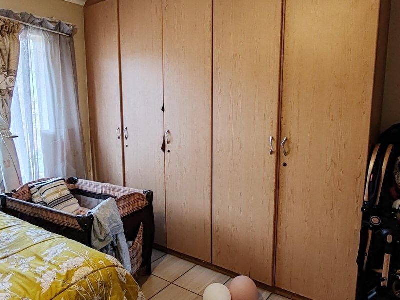 A bedroom featuring built-in wooden cupboards and tiled flooring, providing functional storage space within the room.