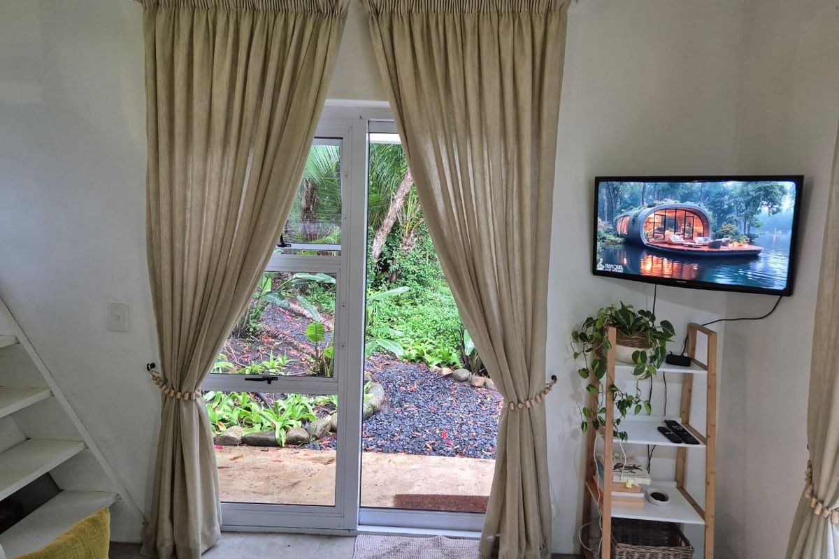 Living area featuring an aluminium sliding door providing direct access to the garden and a staircase leading to the upper level.
