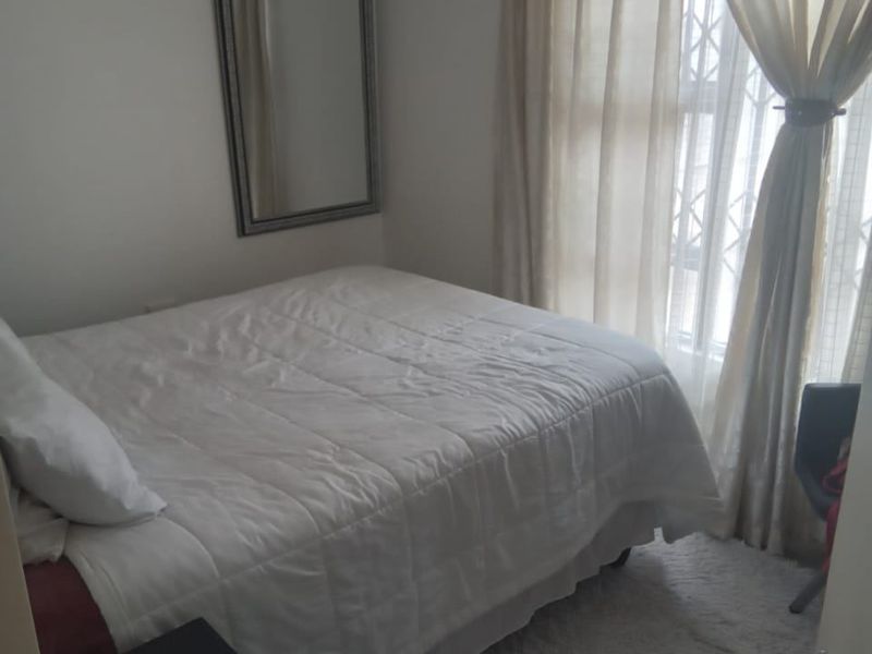 A compact bedroom featuring a window with a security gate and neutral wall finishes.