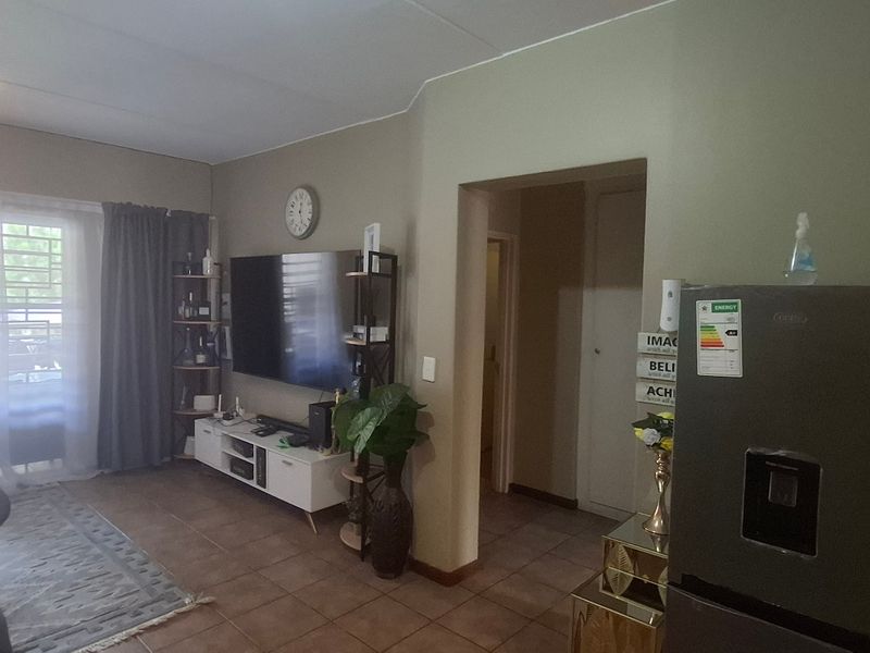 Open plan living area featuring tiled flooring and a sliding glass door leading to a balcony, providing natural light and access to outdoor space.
