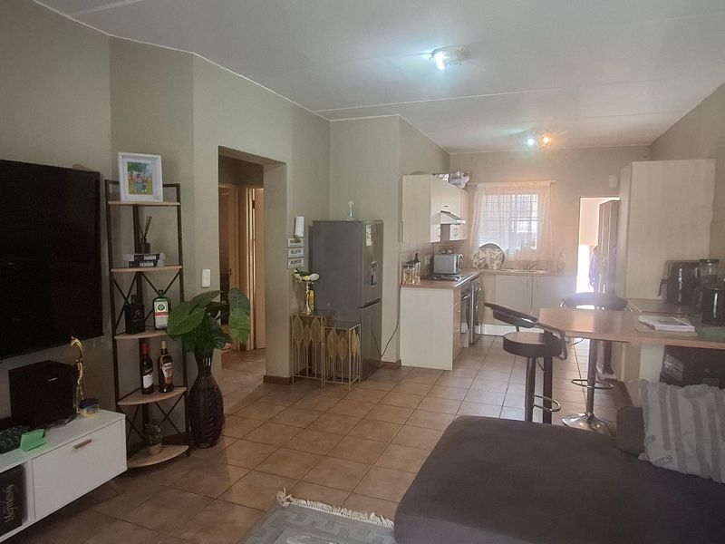 Open-plan living area featuring tiled flooring and a functional kitchen with built-in cabinetry and a breakfast bar.