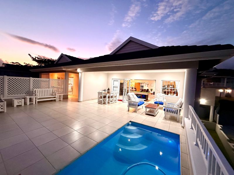 Spacious covered patio area featuring tiled flooring and a swimming pool, perfect for outdoor entertaining at dusk.