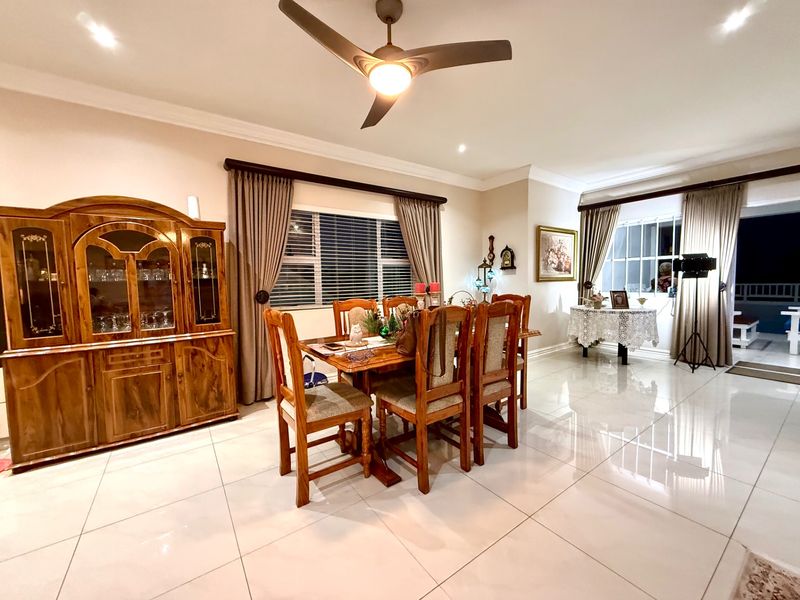 Spacious dining room featuring polished porcelain floor tiles, recessed lighting, a modern ceiling fan, and direct access to an outdoor patio area.