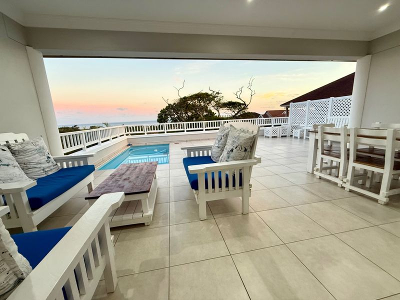 Spacious covered patio featuring tiled flooring, recessed lighting, and a direct view of the swimming pool and horizon.