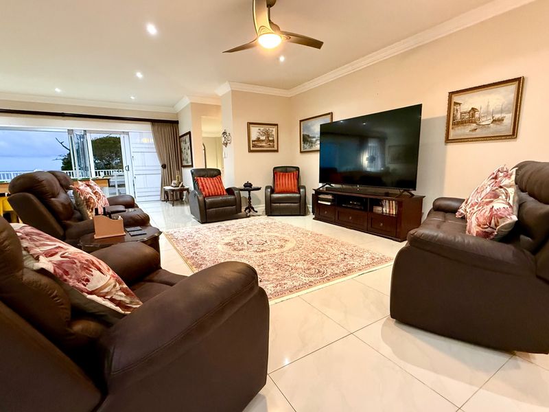 Spacious living room featuring large format floor tiles, recessed lighting, a ceiling fan, and bi-fold doors leading to an outdoor area.
