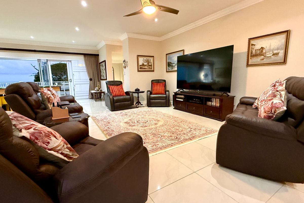 Spacious living room featuring large format floor tiles, recessed lighting, a ceiling fan, and bi-fold doors leading to an outdoor area.