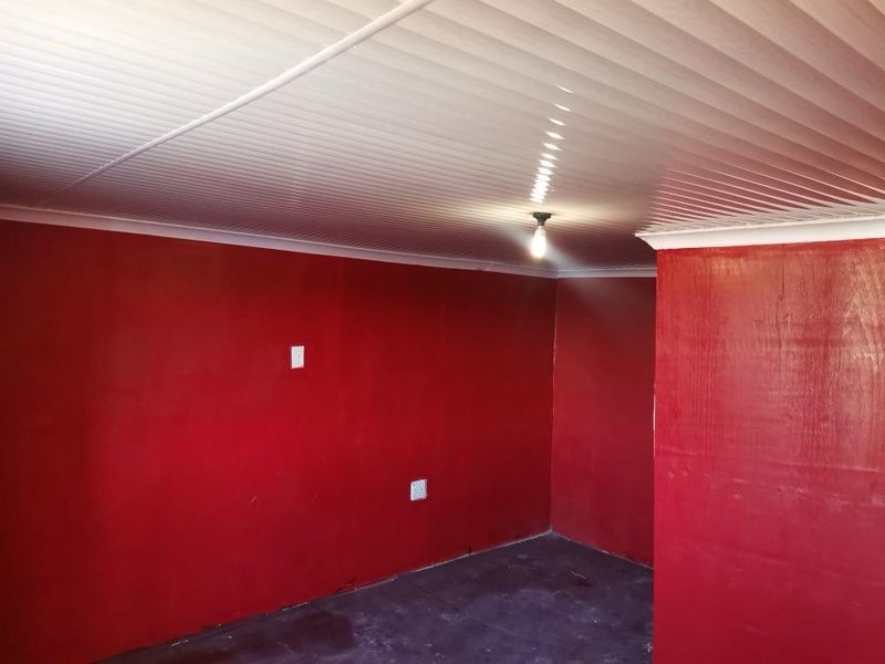An empty room featuring red painted walls and a white PVC panelled ceiling with a central light fixture.