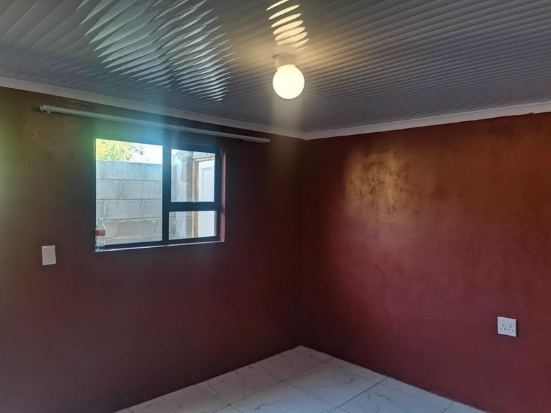 An empty bedroom featuring tiled flooring, aluminium window frames, and a panelled ceiling, ready for personalization.
