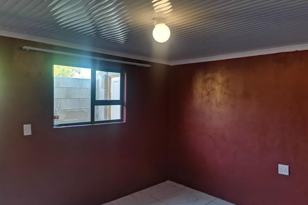 An empty bedroom featuring tiled flooring, aluminium window frames, and a panelled ceiling, ready for personalization.