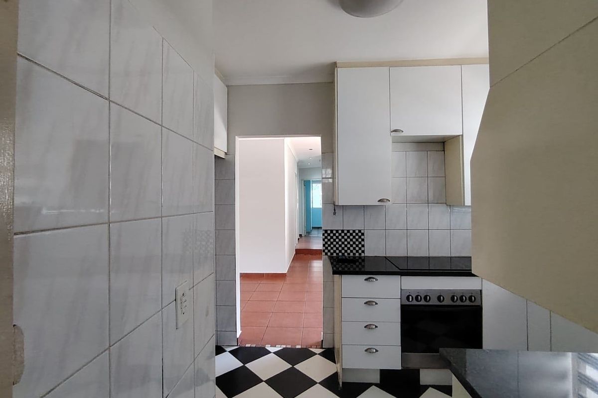 A compact kitchen featuring built-in cabinetry, a built-in oven, and a hob, with a classic black and white checkered tiled floor.