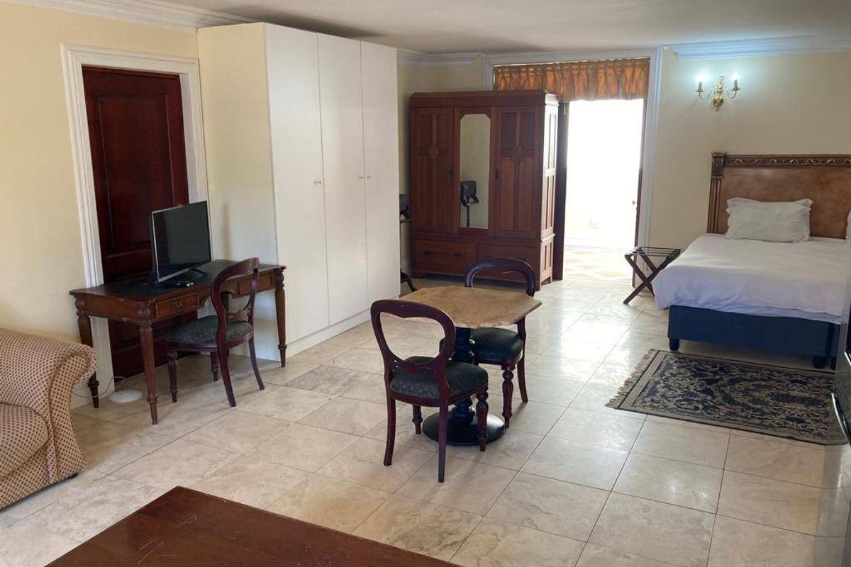 Spacious bedroom featuring tiled flooring, built-in wardrobe storage, and direct access to an outdoor area.