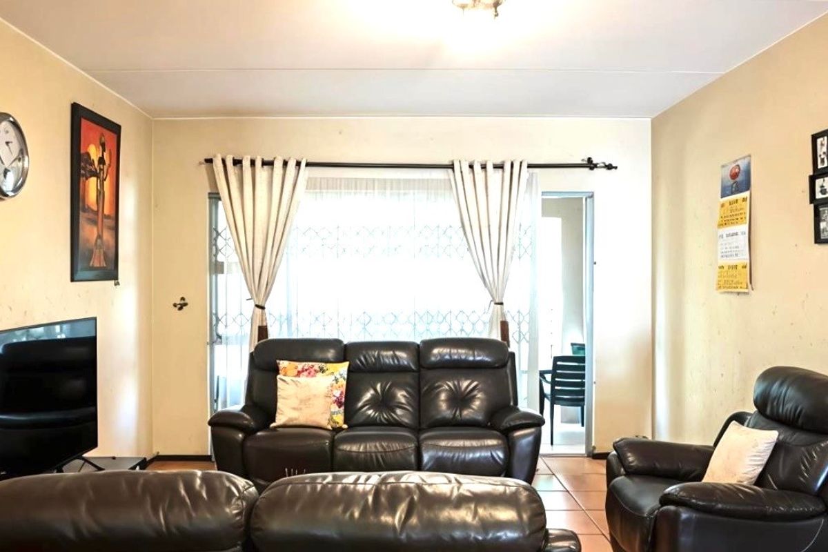 A comfortable living room featuring tiled flooring and a sliding glass door that provides access to an outdoor patio area.