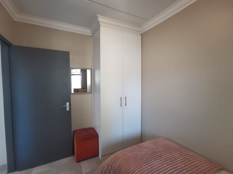 A bedroom featuring a built-in white wardrobe, crown molding, and neutral wall tones, providing a clean and functional living space.