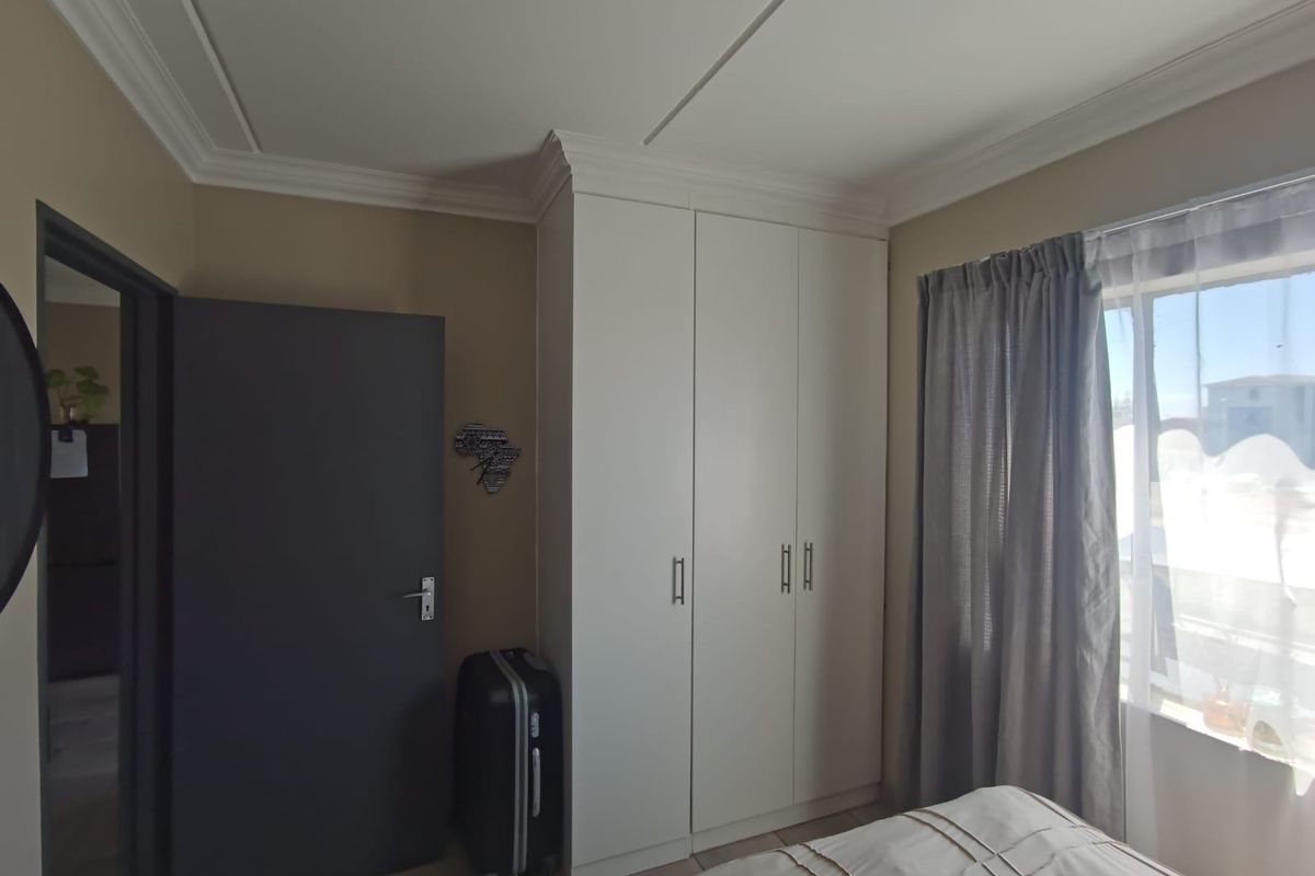 A bedroom featuring built-in wardrobes, crown molding, and tiled flooring, offering a clean and functional living space.