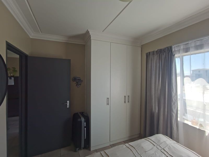 A bedroom featuring built-in wardrobes, crown molding, and tiled flooring, offering a clean and functional living space.