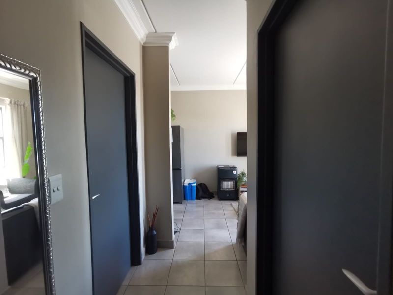 A neutral-toned hallway featuring tiled flooring and modern internal doors, providing access to the main living areas of the apartment.
