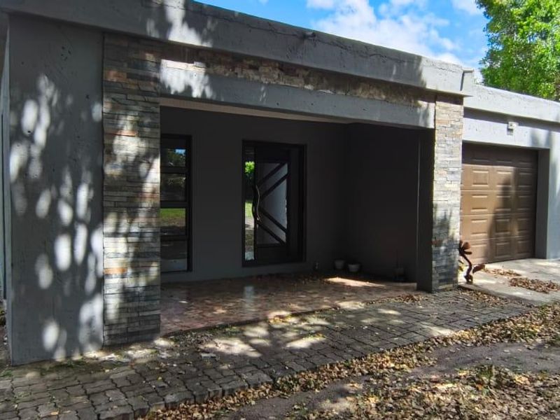 Front exterior view of the house featuring a covered entrance, stone cladding accents, and an attached garage with a paved driveway.