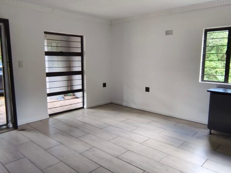An open-plan living area featuring modern tiled flooring, security gates, and built-in kitchen cabinetry, offering a bright and functional space.