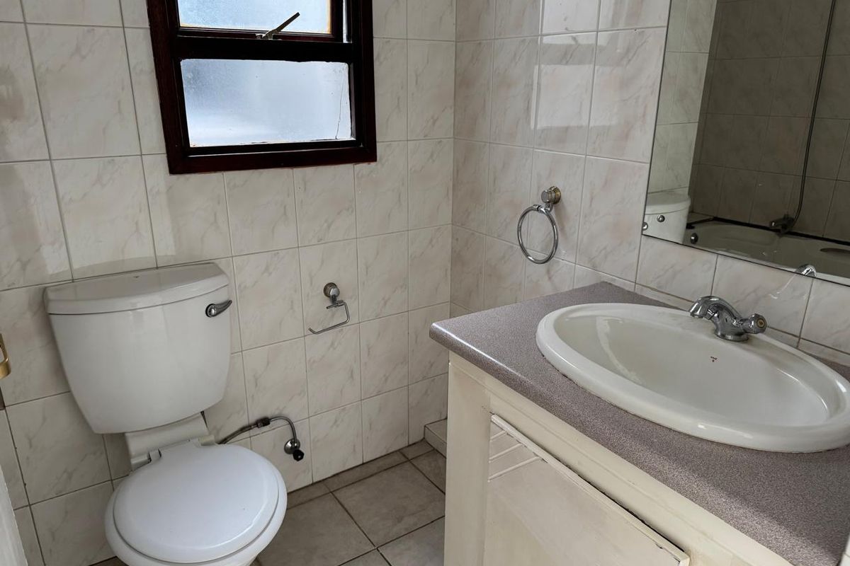 A functional bathroom featuring a vanity cabinet with integrated basin, toilet, and tiled finishes throughout.