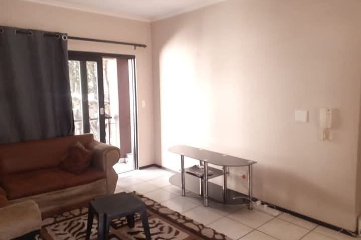 A living room featuring tiled flooring and a sliding glass door providing access to an outdoor area, equipped with a wall-mounted intercom system.