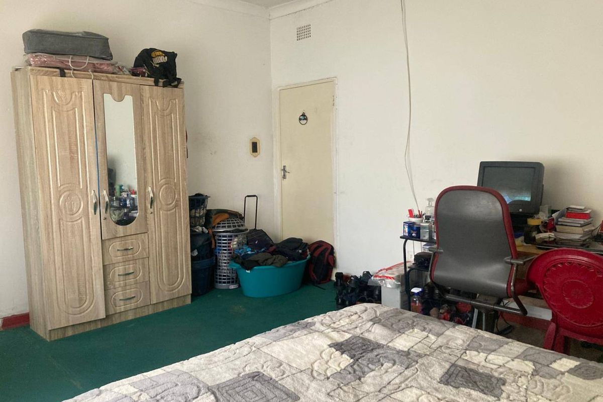 A bedroom featuring green carpet flooring and a standard interior door, offering a functional space ready for cosmetic updates and modernization.