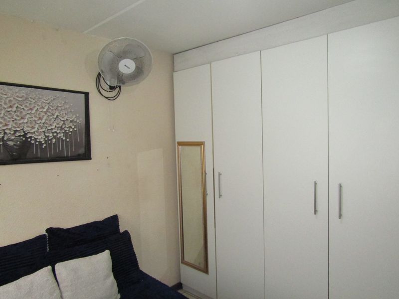 Bedroom featuring white built-in cupboards with integrated mirror panel.