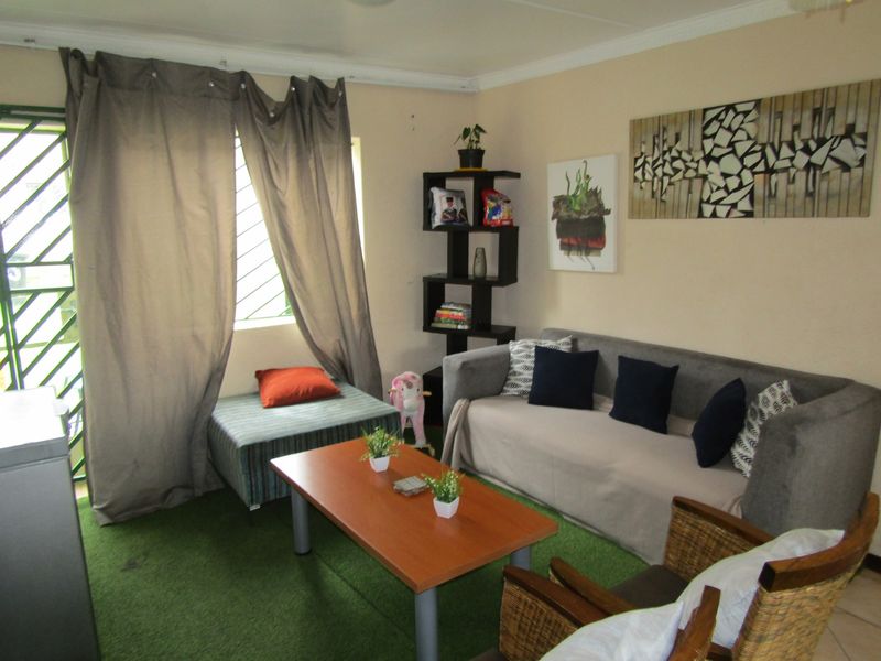 A living room area featuring tiled flooring, decorative cornice, and a security gate leading to the exterior.