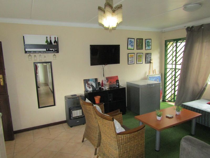A living room area featuring tiled flooring and a security gate, providing a functional space with potential for modernization and aesthetic updates.