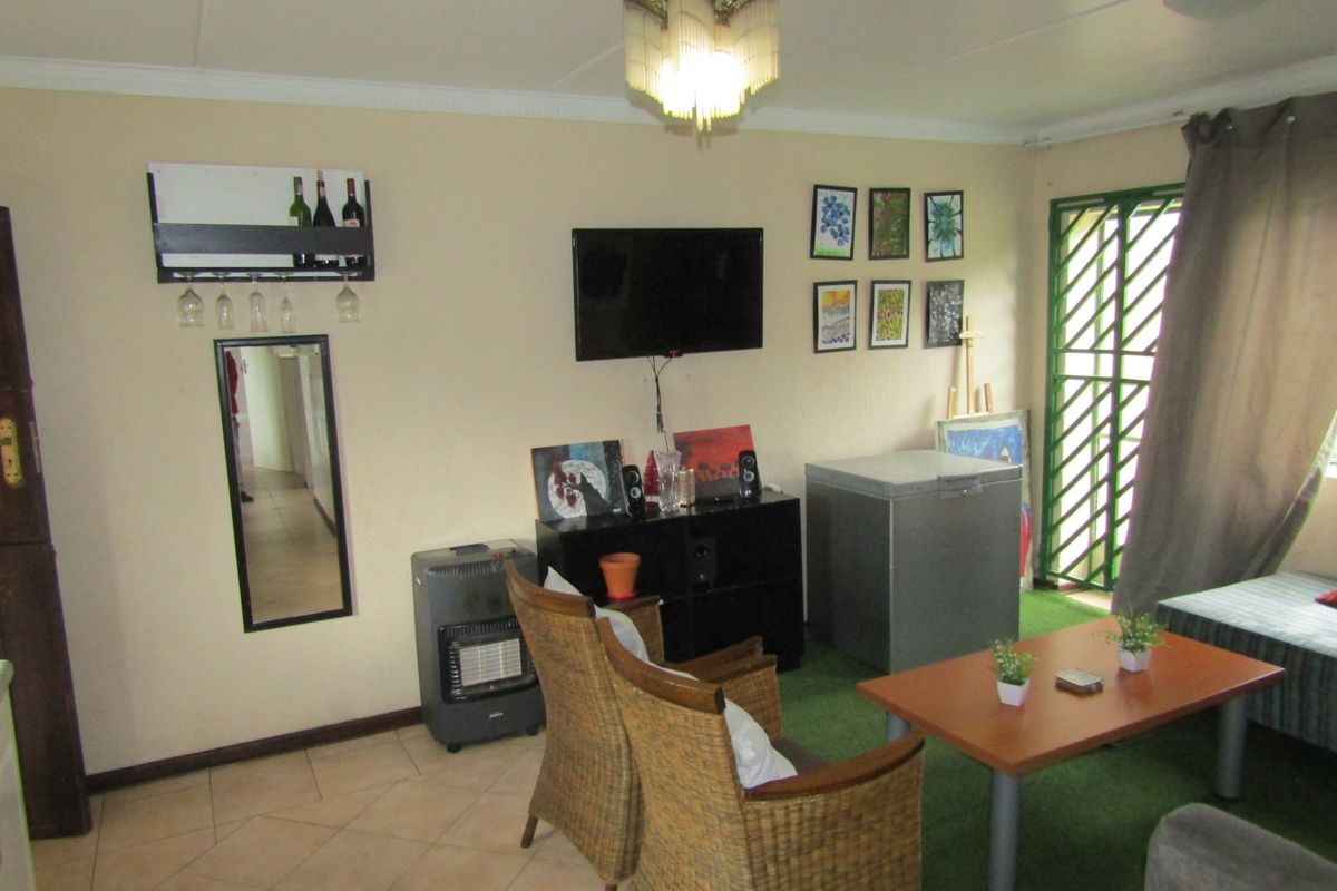 A living room area featuring tiled flooring and a security gate, providing a functional space with potential for modernization and aesthetic updates.