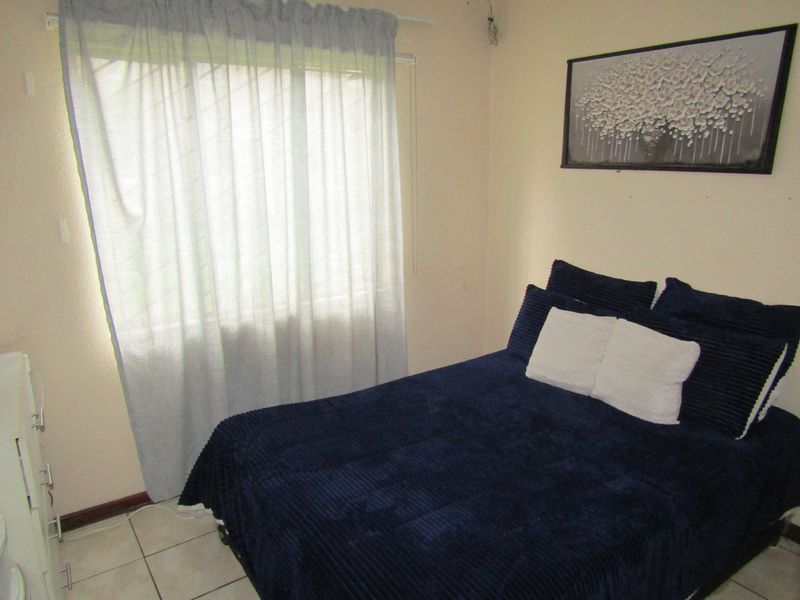 A standard bedroom featuring tiled flooring and a window with a curtain rail, providing a functional space for rest.