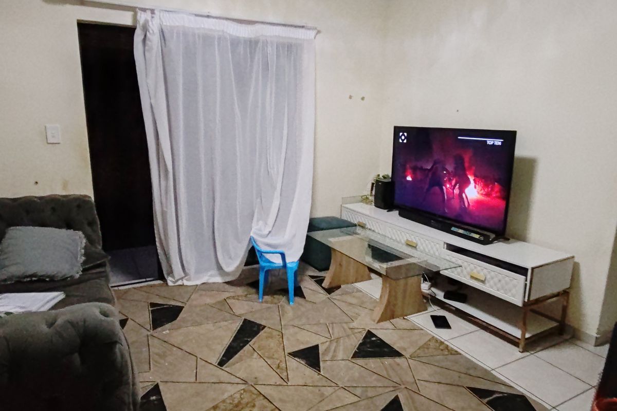 A living room area featuring tiled flooring and access to an outdoor space via a sliding door.